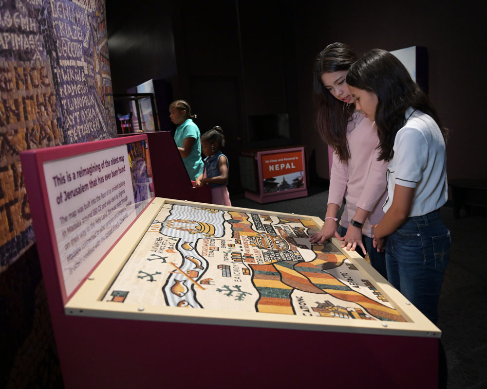 Two older children examining the touchable mosaic map.